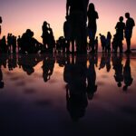 people reflected in water at dusk