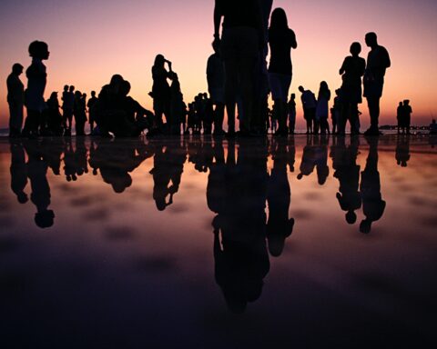people reflected in water at dusk