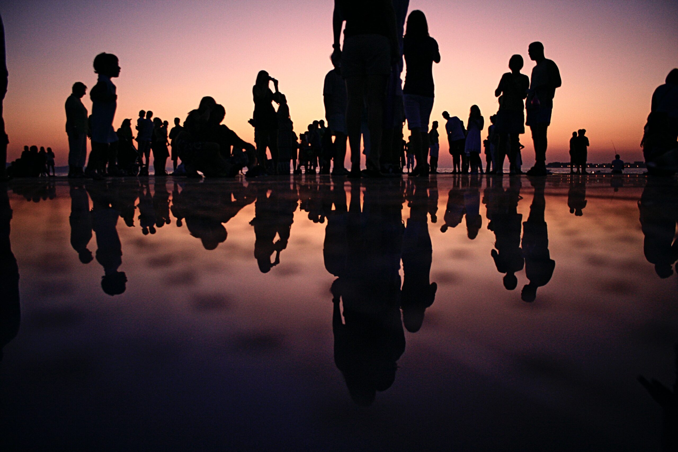 people reflected in water at dusk