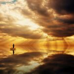 Man fishing on lake in sunrise