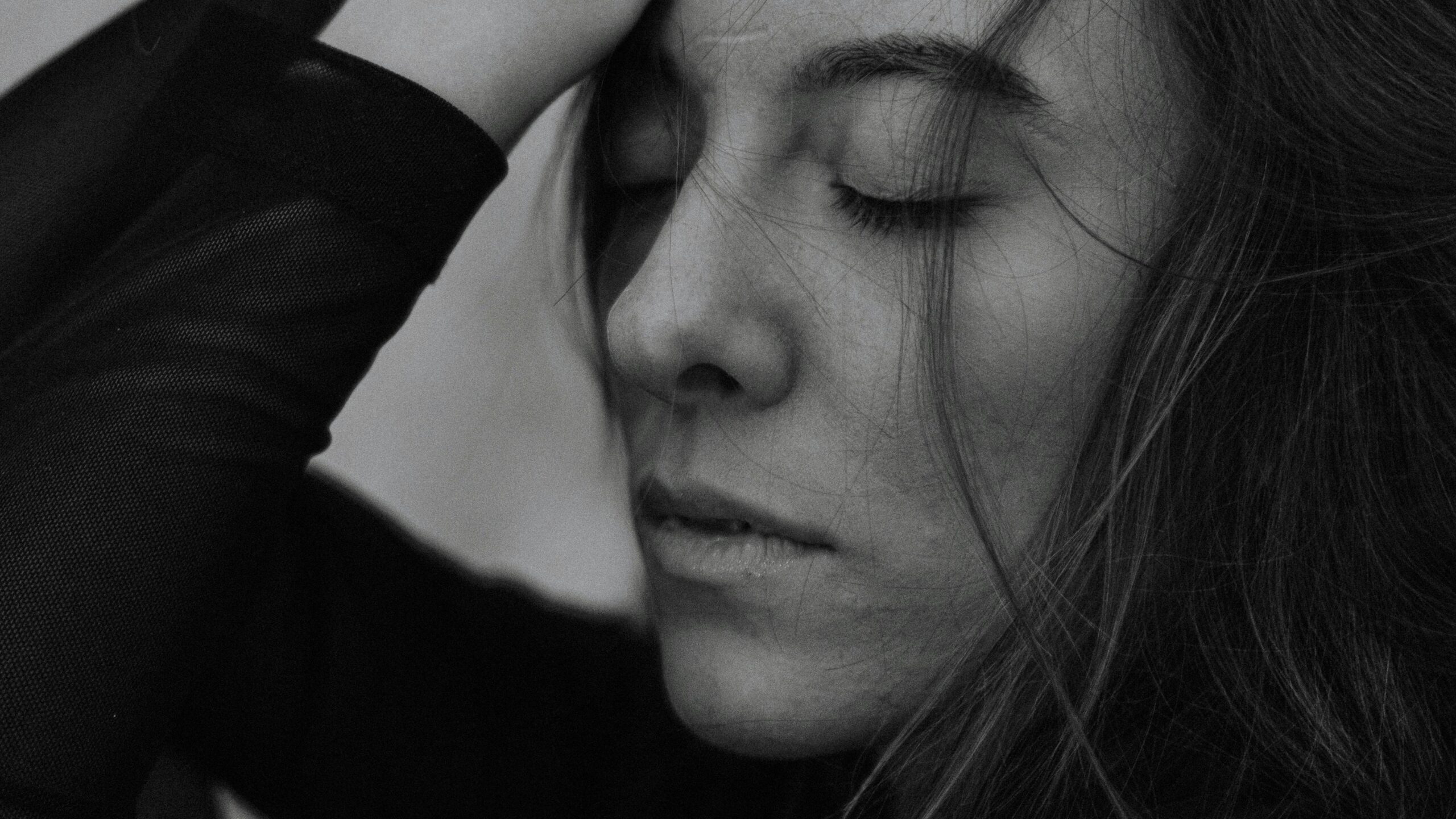 Close-up monochrome portrait of a woman with eyes closed, exuding peace and tranquility.